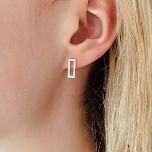 May include: A pair of silver rectangle stud earrings. The earrings are simple and minimalist, with a hollow rectangle design.