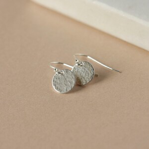 May include: A pair of silver hammered disc earrings with a simple hook fastening.