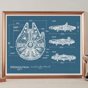 May include: A framed blueprint art print on a blue background featuring technical line drawings of the Millennium Falcon from 1977. The print displays top, side, front, and rear views with detailed labels, measurements in metres, and text.