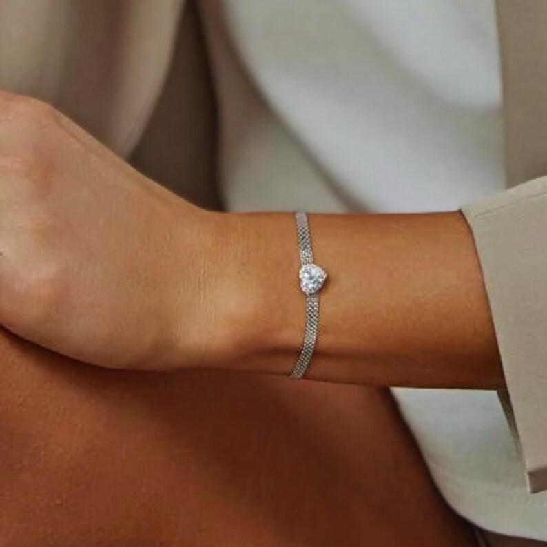 May include: A silver chain bracelet with a heart-shaped clear crystal pendant.