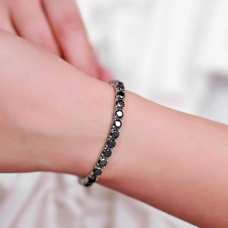 May include: A black diamond tennis bracelet with a silver chain.