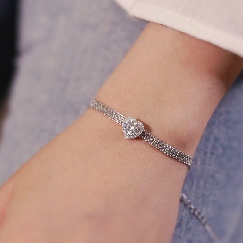 May include: A silver chain bracelet with a heart-shaped clear crystal pendant.