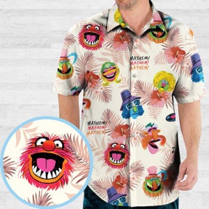 May include: Short-sleeved button-down shirt with a cream background featuring colorful Muppet characters and tropical flowers. The shirt has the text "MAYHEM!" repeated throughout the design. A close-up shows a pink, furry character with a wide grin.