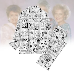 Può includere: Set pigiama bianco con stampa grafica in bianco e nero di personaggi dei cartoni animati, rose e testo. La parte superiore a maniche lunghe ha bottoni e colletto. I pantaloni hanno un elastico in vita. Il testo include "Golden", "Sicily" e "Shady Pines".