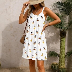 Może przedstawiać: Biała sukienka letnia z powtarzającym się wzorem Myszki Miki i Pluto. Sukienka ma cienkie ramiączka i marszczony dekolt. Sukienka do kolan jest odpowiednia na ciepłą pogodę. Sukienka jest wykonana z lekkiego materiału.