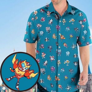 May include: Teal short-sleeve button-up shirt featuring a repeating pattern of colorful cartoon robots. The shirt has a classic collar and silver buttons. A circular graphic of a robot in red, yellow, and orange is in the lower left corner.