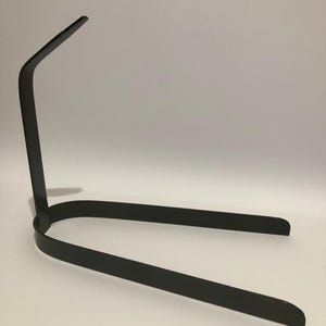 Puede incluir: Un soporte de metal negro con un diseño curvo. El soporte está hecho de una sola pieza de metal y tiene una estética simple y moderna.
