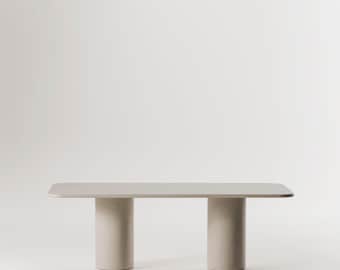 May include: A light beige rectangular dining table with a smooth, flat top and two cylindrical legs. The table is on a white background.