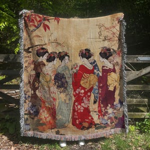 以下が含まれることがあります： 伝統的な日本の衣装を着た6人の女性がカラフルに描かれた織りのタペストリー毛布。女性たちは一列に並んでおり、背景は花柄です。