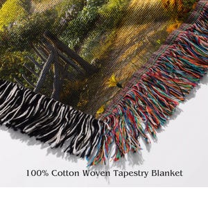 K&ouml;nnte beinhalten: Eine gewebte Wandteppichdecke mit einem bunten Fransen. Die Decke zeigt eine Landschaftsszene mit einem Holzzaun und gr&uuml;nem Laub. Der Text "100% Cotton Woven Tapestry Blanket" ist unter dem Bild gedruckt.