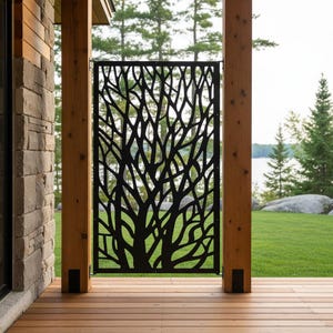 May include: A rectangular black metal privacy screen featuring a laser-cut design of intricate, branching tree limbs. The panel is mounted vertically between two wooden support posts on a wooden deck, creating a decorative barrier.