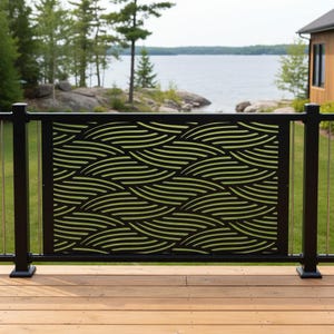 May include: A rectangular black metal railing panel featuring a laser-cut pattern of repeating, flowing wave-like lines. The panel is mounted between two black vertical posts on a wooden deck, showcasing a decorative design with cutouts.