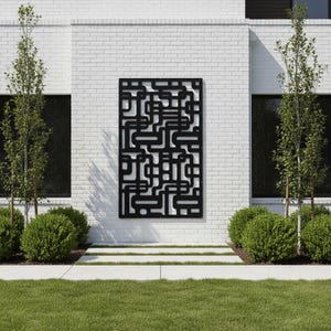 May include: A rectangular black metal wall panel featuring a complex, continuous geometric maze pattern of interconnected lines and rounded corners, mounted vertically on a white brick exterior wall between two dark windows.