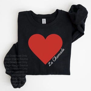 May include: Black crew neck sweatshirt with a large red heart design. The words "La Chamade" are printed in white script on the lower right of the heart. The sweatshirt is made of a soft material.