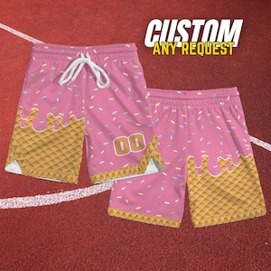 May include: Pink basketball shorts with a donut design. The shorts feature a pink base with a waffle cone pattern at the bottom and sprinkles. The text "CUSTOM ANY REQUEST" is at the top.