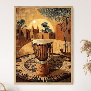 May include: A framed art print depicts a djembe drum in an African village scene. The drum is brown with a light-colored drumhead, set on a patterned mat. The background features buildings, trees, and a sun, all in warm, earthy tones.