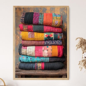 May include: A framed image showcases a stack of colorful, patchwork quilts. The quilts, in shades of red, orange, yellow, blue, and black, are neatly arranged on a wooden surface. The quilts have a vintage, handcrafted appearance, with visible stitching and varied fabric patterns.