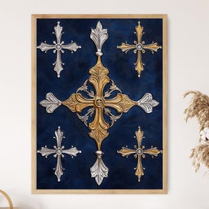 May include: Framed artwork with a dark blue backdrop, showcasing gold and silver ornate crosses. The central cross is large and detailed, with smaller crosses surrounding it. The frame is a light wood colour.