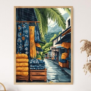 Könnte beinhalten: Ein gerahmter Druck einer lebhaften Straßenszene. Das Kunstwerk zeigt einen Markt mit blauen floralen Textilien und Stapeln gelber Garne. Palmen und Gebäude säumen die Straße und schaffen eine tropische Atmosphäre.