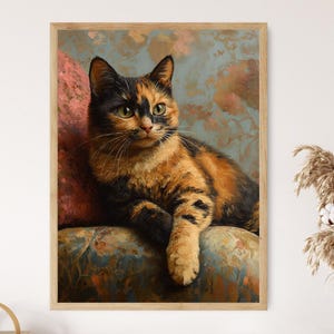 Op de afbeelding: Een schilderij van een schildpadkat met groene ogen die op een gepatroneerd kussen zit. De kat kijkt naar rechts van het frame. De achtergrond is gedempt blauw met een bloemenpatroon.