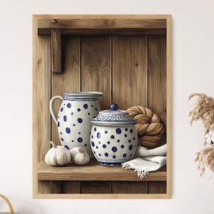 May include: A framed print featuring a still life of kitchenware. A blue and white polka-dotted pitcher and jar sit on a wooden shelf with two garlic bulbs. A braided bread and a folded white cloth complete the scene.