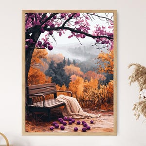 May include: A framed art print depicts a serene autumn scene. A wooden bench sits beneath a tree with purple leaves and fruit. The background features a forest with orange and yellow foliage, and a blanket rests on the bench.