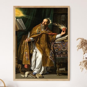 May include: Framed print of a religious painting. The artwork depicts a man in gold and red robes holding a flaming heart and a quill. The background includes books, a table, and a dark green curtain. The painting is in a wooden frame.