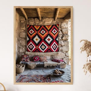 May include: A red, black and white patterned rug hangs on a stone wall in a rustic room. A wooden bench with cushions sits in front of the rug. The room has a wooden ceiling and a stone floor.