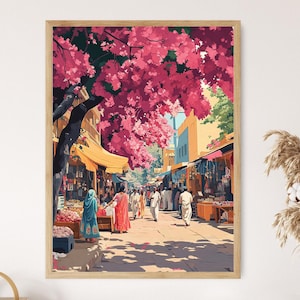 May include: A framed art print depicting a bustling street scene. The artwork features a vibrant pink flowering tree canopying a marketplace with people in traditional clothing. The buildings are painted in warm tones, and the scene is filled with light and shadow.