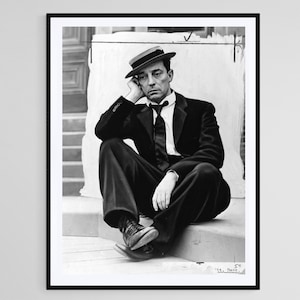Puede incluir: Impresión enmarcada en blanco y negro de un hombre con traje y sombrero, sentado en unos escalones. El hombre apoya la cabeza en la mano, con expresión contemplativa. Un retrato clásico, ideal para la decoración.