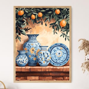 May include: A framed print featuring a still life of blue and white ceramic vases and a plate with floral designs. The artwork includes orange fruit and green foliage, set against a warm, textured background. The vases are arranged on a brick ledge.