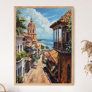 Op de afbeelding: Een ingelijst schilderij toont een zonnige straatscène met gebouwen en een koepelvormige structuur. Het kunstwerk heeft een warm kleurenpalet van oranje, bruin en blauw, met uitzicht op de oceaan. Het schilderij zit in een houten lijst.