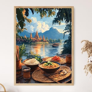 Op de afbeelding: Een schilderij van een tempel in Thailand met een rivier op de voorgrond. Het schilderij is ingelijst in hout en heeft een rustieke uitstraling. Op een tafel op de voorgrond staat een kom met noedels, een kom met rijst en een bord met rode paprika's.