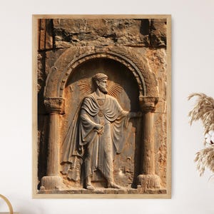 May include: A framed print of a carved relief sculpture depicting a robed figure with a halo, holding an object. The artwork is in shades of brown and tan, with a classical architectural setting.