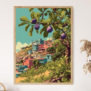 May include: A framed art print featuring a colorful illustration of a hillside town with red, blue, and green buildings. The artwork includes a tree with purple fruit and green leaves, set against a blue sky. The print is in a wooden frame.