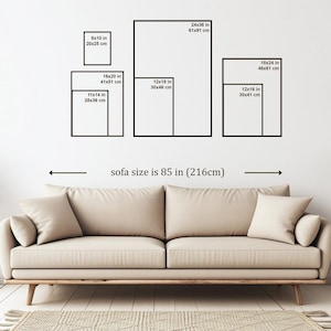 May include: A beige sofa with two throw pillows is positioned below a wall displaying framed art prints of various sizes, including 8x10 inches, 11x14 inches, 12x16 inches, 12x18 inches, 16x20 inches, 18x24 inches, and 24x36 inches. The sofa's length is 85 inches.