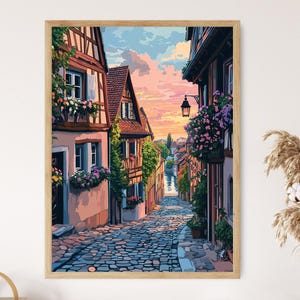 May include: A painting depicting a narrow cobbled street in a European village. The street is lined with colourful buildings featuring flower boxes and a view of a river in the distance. The sky is a soft pink and blue.