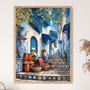 May include: A framed print of a watercolor painting depicting a blue and white alleyway scene. A woman sits near a doorway, surrounded by jars and baskets. The scene includes stairs, arches, and decorative elements.