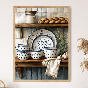 May include: A framed watercolor painting of a kitchen shelf with blue and white polka-dot dishes, a loaf of bread, and a jar. The shelf also holds a white cloth, garlic, and decorative plants. The artwork has a rustic, farmhouse aesthetic.