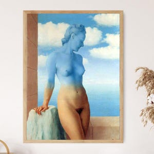 May include: A framed print of a surrealist painting. The artwork depicts a nude figure with a blue upper body and a tan lower body, set against a backdrop of a blue sky with white clouds and a seascape. The figure is leaning on a stone structure.