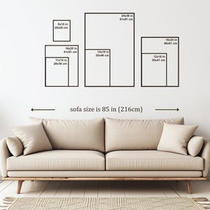 May include: A beige sofa with two throw pillows is positioned below a white wall displaying framed art prints of various sizes, including 20x25 cm, 28x36 cm, 30x41 cm, 30x46 cm, 41x51 cm, 46x61 cm, and 61x91 cm. The sofa is 216cm wide.