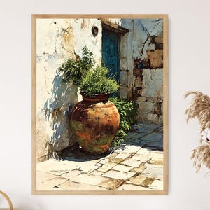 May include: A framed art print depicts a sunlit courtyard scene. A large, weathered terracotta pot overflowing with greenery sits against a textured white wall. A blue door and stone pathway add depth to the composition. The artwork is framed in a light wood.