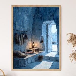 Op de afbeelding: Een blauw getint schilderij in een lijst van een interieurscène. Het kunstwerk toont een rustieke kamer met een stenen bank, een hangrek met voedsel en een brandende lantaarn. Een deuropening leidt naar een zonnige buitenscène.