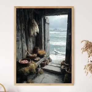 May include: A framed print of a coastal scene. The artwork depicts an open doorway leading to a beach with a seagull. Inside the doorway are bowls and dried plants. The color palette is muted with shades of gray, brown, and blue.