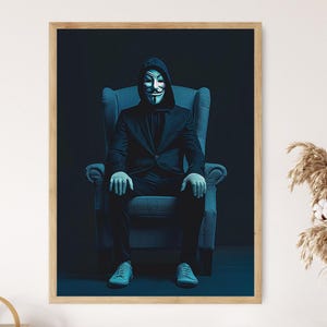 May include: Framed print of a person in a black suit and Guy Fawkes mask, seated in a blue armchair. The image has a dark, moody aesthetic, with the central figure in focus. The print is presented in a wooden frame.