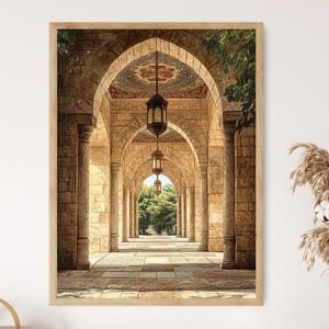 May include: A framed print of an arched corridor with stone columns and a patterned ceiling. Hanging lanterns illuminate the pathway, leading to a view of trees and sunlight. The artwork is in a wooden frame.