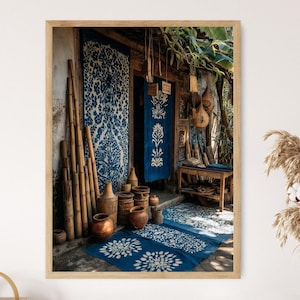 Op de afbeelding: Een ingelijste foto van een winkelingang met blauw-witte patronen. Bamboe palen leunen tegen de muur. Verschillende aardewerken vaten en tapijten met bloemmotieven zijn zichtbaar. De scène baadt in natuurlijk licht.