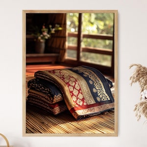 以下が含まれることがあります： 金、赤、紺色の複雑な模様が施された、折りたたまれた織物の額装画像。 織物は竹のマットの上に重ねられており、窓と花瓶のぼやけた背景があります。