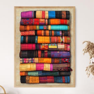 May include: A framed print featuring a stack of colorful, patterned textiles. The textiles display a variety of colors including red, blue, yellow, and purple. The textiles are stacked vertically, creating a visually appealing display.