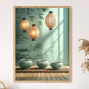 May include: A framed print featuring a serene Asian-inspired scene. Three glowing paper lanterns hang above three small, green ceramic bowls with floral designs. The background includes bamboo leaves and a light green wall.